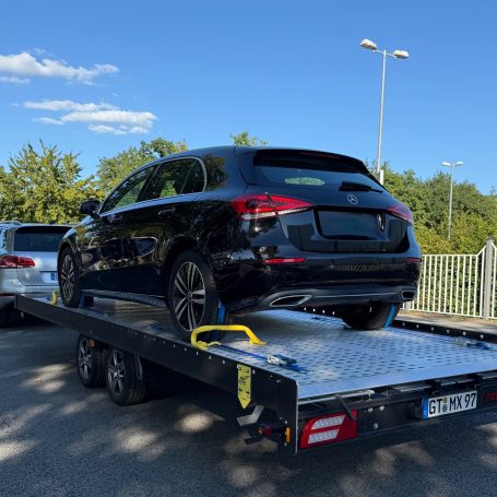 Heckansicht einer schwarzen Mercedes A-Klasse auf dem Transportanhänger von MHX Fahrzeugtransporte