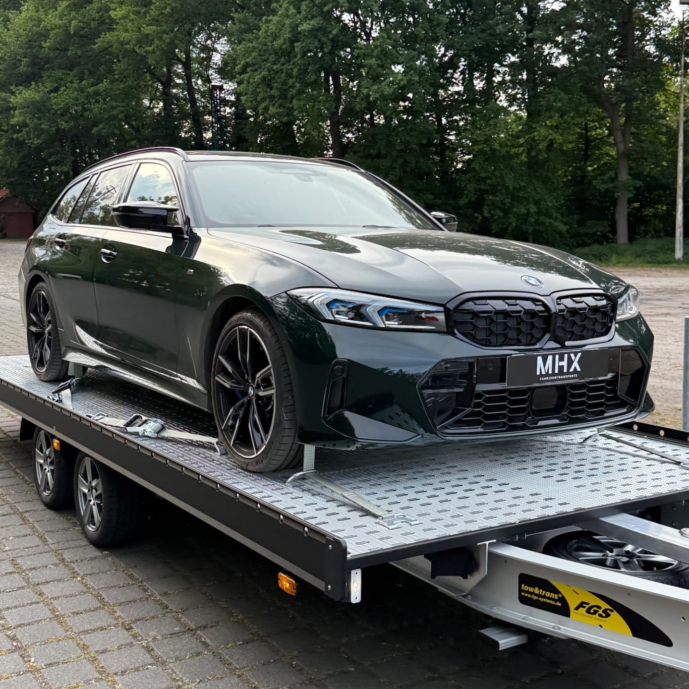 Transport eines grünen BMW 3er Touring durch MHX Fahrzeugtransporte aus Gütersloh