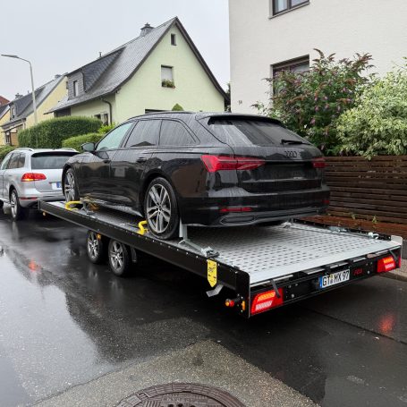 Heckansicht des schwarzen Audi A6 Avant auf dem Transportanhänger von MHX Fahrzeugtransporte