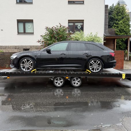 Seitenansicht eines Audi A6 Avant in Schwarz auf dem Autotransporter von MHX Fahrzeugtransporte